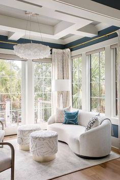 a living room filled with white furniture and lots of window sill space next to large windows