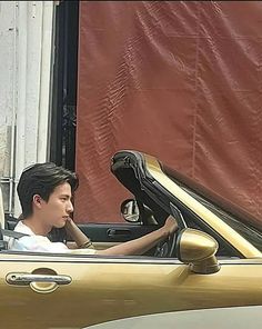 a man sitting in the driver's seat of a convertible car