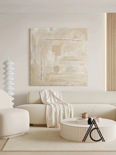 a living room with white furniture and art on the wall