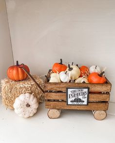 pumpkins and gourds sit in a wooden crate on a white surface next to hay