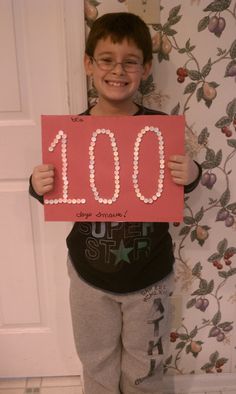 a young boy holding up a sign that says 100