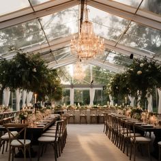 the inside of a tent with tables, chairs and chandeliers set up for an event