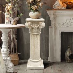 a vase with flowers sitting on top of a pedestal next to a fire place in a living room