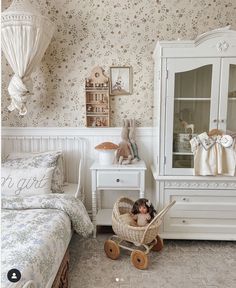 a doll sitting in a basket next to a white dresser and baby's crib