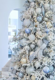 a white christmas tree with silver and blue ornaments