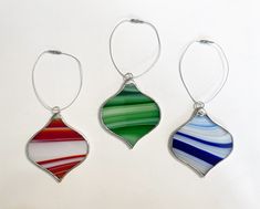 three different colored glass ornaments hanging from silver wire