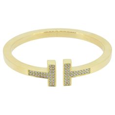 Here we have a modern, sophisticated bangle from the world renowned jewellery designer, Tiffany & Co. An 18ct yellow gold bracelet has been crafted into Tiffany's iconic double T design and pavé set with 60 round brilliant cut diamonds. Condition: Used (Excellent) Weight: 33.8 grams Inside Diameter: 57mm Size: Medium - Fits Wrist up to 6.25 Total Diamond Weight: Approx. 0.74ct Band Width: 4.5mm Marked: 'TIFFANY&Co' 'AU750' & 'ITALY RRP: £16,300 Documents: The Vintage Jeweller Guarantee of Authen Gold Tiffany Bracelet, Tiffany Bracelet, Gold Tiffany, Square Bracelet, Tiffany T, Tiffany Bracelets, T Design, Jewellery Designer, Tiffany And Co