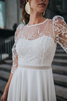 a woman in a white dress is standing outside