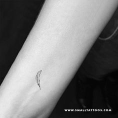 a small feather tattoo on the left inner forearm and wristband is shown in black and white