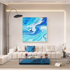 a living room with white couches and blue art on the wall above it,