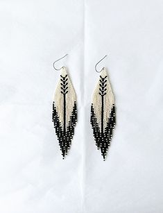 I have just loved creating these woven treasures. These simple, elegant earrings have been handwoven one bead at a time using Czech glass seed beads, bugle beads and strong synthetic string. They are finished with a stainless steel ear wires. They are light and delicate and perfect for any occasion. Colour: Eggshell/Cream and Black Length: 12.5 cm with a 13.5 cm drop Width: Triangular Shape 3 cm Beaded fringe earrings have a memory so please either hang or lay flat when not wearing. For other ea Fringe Stud Earrings, Cheap Handwoven Beaded Earrings For Gift, Bohemian Beaded Dangle Wrap Earrings, Woven Drop Earrings, Artisan Woven Dangle Earrings, Woven Beaded Dangle Earrings For Gifts, Woven Beaded Drop Earrings As Gift, Gift Woven Beaded Drop Earrings, Elegant Woven Drop Earrings