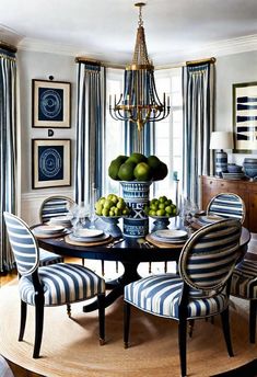 a dining room with striped chairs and a chandelier hanging from the ceiling over a round table