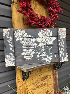 an old wooden box with flowers painted on it is hanging from the side of a house