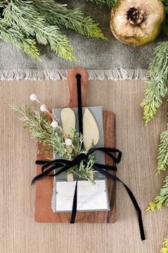 a cutting board and knife on top of a table next to some christmas tree branches