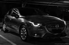 a black and white photo of a car parked in a parking lot with the lights on