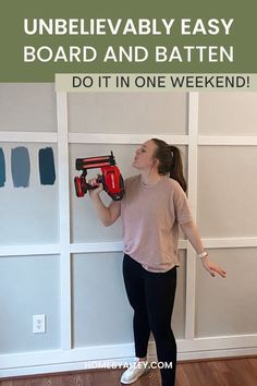 An image of a women holding a nail gun in front of a board and batten wall. The text says "Unbelievably Easy Board and Batten Wall" Diy Board And Batten Wall Mdf, How To Build Board And Batten Wall, Board And Batten All One Color, Cheap And Easy Board And Batten, Easiest Board And Batten Wall, Board And Batten Wall Diy Cheap, Board And Batten Office Wall Ideas, Board And Batten Entire Wall, Batten Board Walls Diy