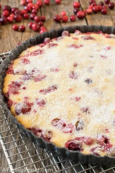 a pie sitting on top of a metal pan covered in berries next to a wire rack