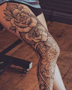 a woman's leg with a flower tattoo on it and an intricate lacework design