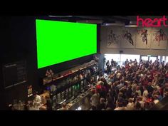 a large group of people standing in front of a green screen at a restaurant or bar