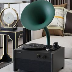 a record player sitting on top of a table next to a lamp and couch in a living room