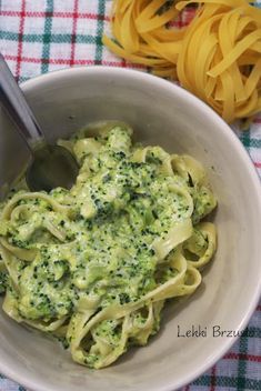 a bowl filled with pasta and broccoli on top of a checkered table cloth