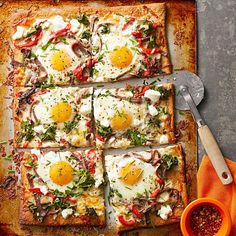 several square pizzas with eggs on them and sauce in the middle, sitting on a cutting board