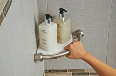 a person is holding onto a soap and lotion dispenser in a bathroom