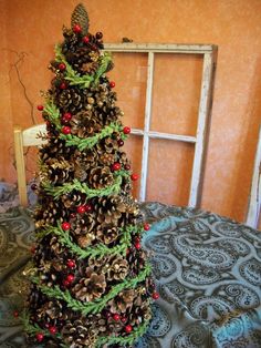 a pine cone christmas tree sitting on top of a blue table cloth next to an old window