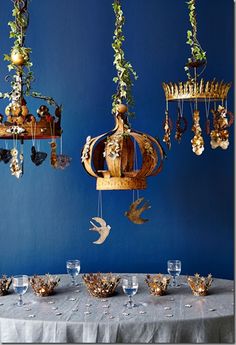 a table topped with lots of plates and cups under chandelier hanging from the ceiling