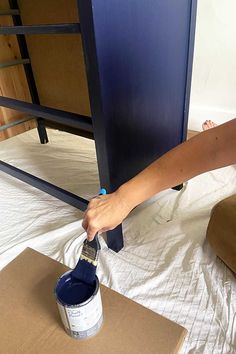 a person is painting the bottom of a bunk bed with blue paint and cardboard boxes