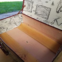 an open suitcase sitting on top of a wooden floor next to a grass covered field