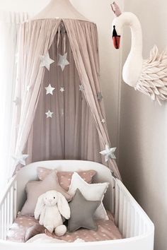 a baby crib with a white swan hanging from it's side and stars on the ceiling