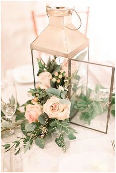 a table topped with a vase filled with flowers and greenery