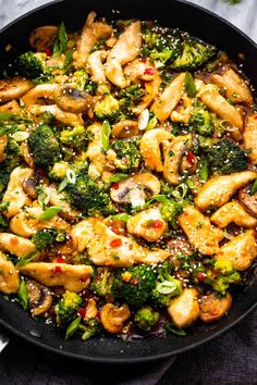 chicken and broccoli stir frying in a skillet on top of a table