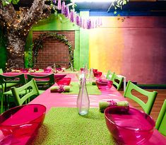 the table is set with bright pink and green chairs