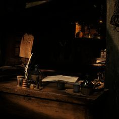 an old fashioned desk with writing utensils and other items on it in a dark room