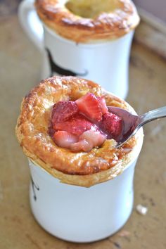 two white cups filled with pastries on top of a table