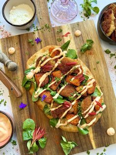 a pizza sitting on top of a wooden cutting board next to other food and condiments