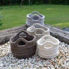 four crocheted baskets sitting on top of a pile of rocks