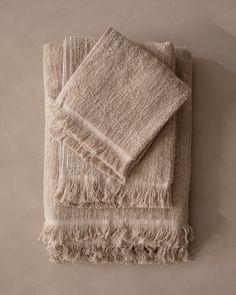 two white towels folded on top of each other with fringes around the edges and bottom