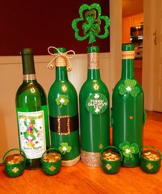 four green bottles with shamrock decorations on them