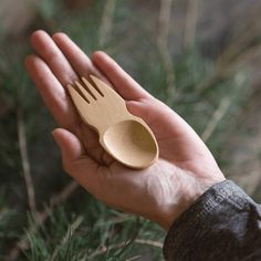 a hand holding a wooden spoon and fork