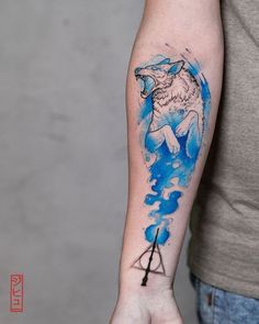 a man's arm with a blue ink painting on it and a wolf in the sky