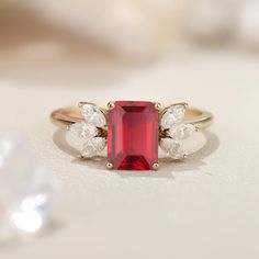 a close up of a ring with a red stone and two white stones on it