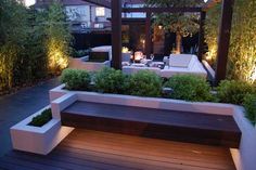 an outdoor seating area is lit up with lights and greenery on the decking