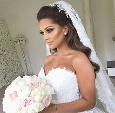 a woman in a wedding dress holding a bridal bouquet and looking at the camera