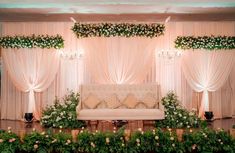 a couch sitting in front of a window covered in flowers and greenery next to plants