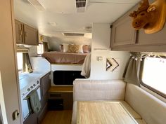 the interior of an rv with wood flooring and white walls, including a bed