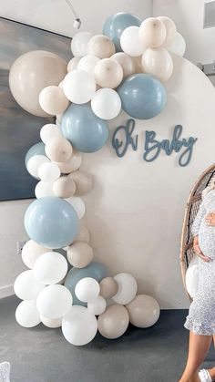 a pregnant woman standing next to balloons and a sign that says k baby on it