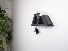 a wooden clock mounted to the side of a wall next to a key holder and potted plant